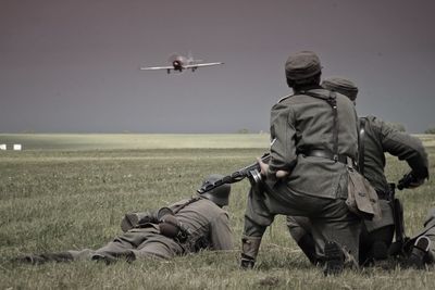 Airplane flying over field against sky