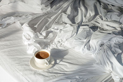 High angle view of coffee cup on bed