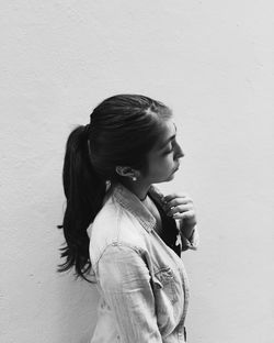 Side view of young woman standing by wall