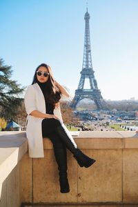 Portrait of smiling young woman sitting on eiffel tower
