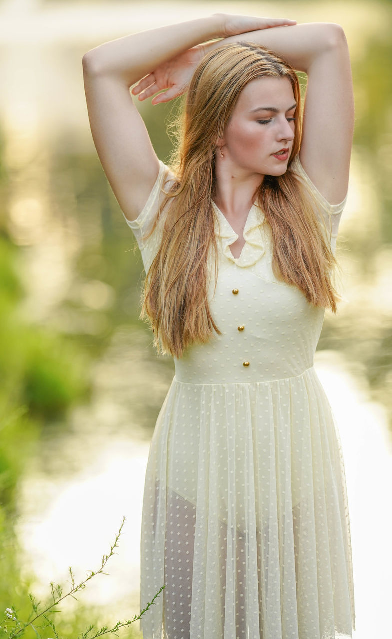 women, long hair, one person, hairstyle, young adult, adult, blond hair, dress, fashion, clothing, nature, portrait, summer, standing, emotion, smiling, happiness, three quarter length, hand in hair, plant, outdoors, looking, gown, brown hair, female, portrait photography, day, photo shoot, green, child, grass, elegance, front view, relaxation, beauty in nature, human hair, sunlight, contemplation, pink, focus on foreground, waist up, person, leisure activity, lifestyles, environment, rural scene, positive emotion, carefree