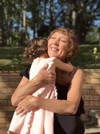 Little girl hugging woman in the garden 