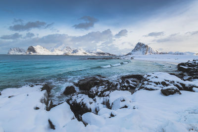 Scenic view of sea and snowcapped mountains against sky