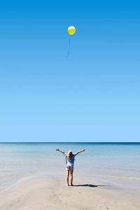 Rear view of person standing on beach against clear sky