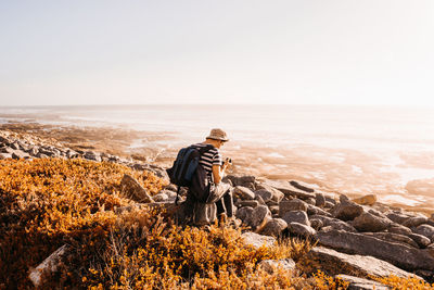 Rear view of man standing on rock against sky