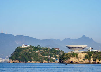 Scenic view of sea and mountains against clear sky