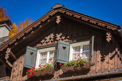 Wooden gable of typical austrian rustic house with two windows, shutters and flower boxes