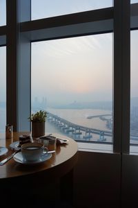 Close-up of table by window against sky