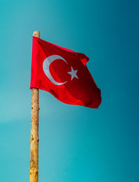 Low angle view of red flag against blue sky