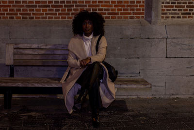 Portrait of young woman standing against wall