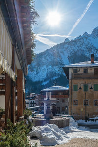 Houses by snowcapped mountains against sky during winter