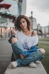 Portrait of beautiful young woman sitting in city