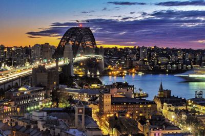 Illuminated cityscape against sky during sunset