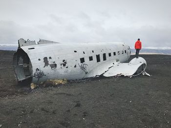 Man standing on abandoned airplane against sky