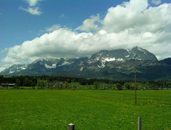 Scenic view of grassy field against cloudy sky