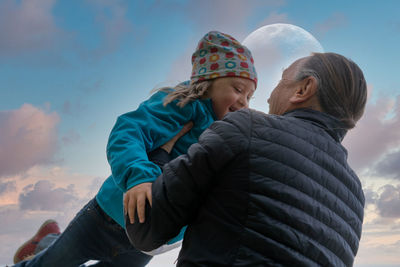 Rear view of father and daughter against sky