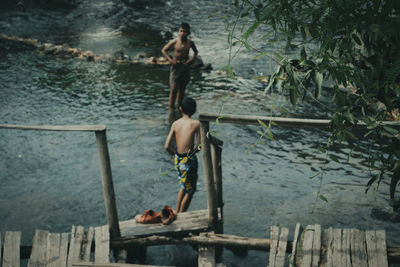 Rear view of shirtless men in water