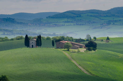 Scenic view of field by buildings against sky