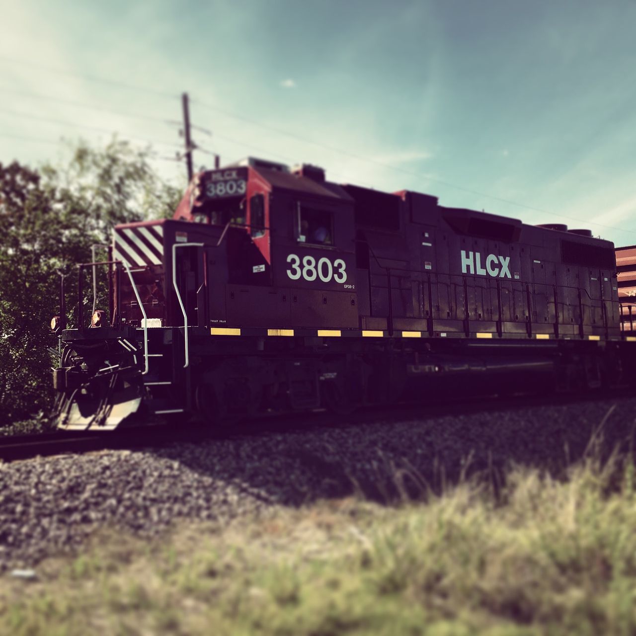 transportation, text, sky, western script, mode of transport, public transportation, rail transportation, railroad track, communication, train - vehicle, land vehicle, car, travel, information sign, cloud - sky, day, road, outdoors, on the move, tree