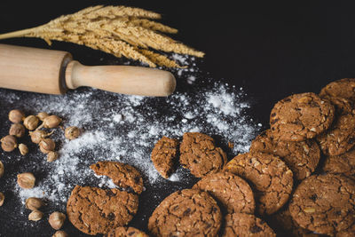 High angle view of chocolate chip cookies and rolling pin on black background