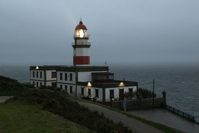 Lighthouse by sea against sky at dusk