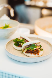 Vertical view of the appetizer serving on white plate at restaurant background. bau buns food