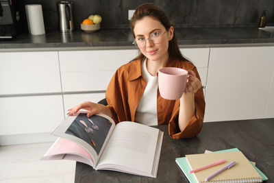 Portrait of young woman using laptop at table