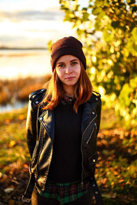 Portrait of beautiful young woman standing on field during autumn