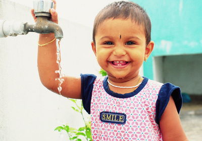 Close-up portrait of smiling boy standing in water