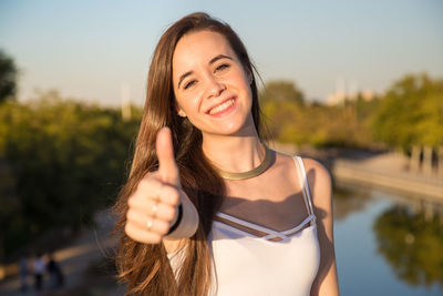 Portrait of smiling young woman against lake