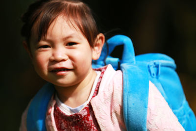 Portrait of smiling girl with backpack in park