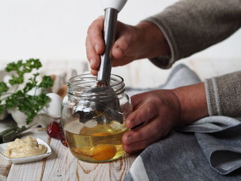Midsection of person preparing food in glass jar on table