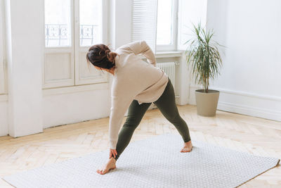 Attractive middle aged brunette woman in sportswear practice yoga in the light studio