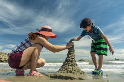 Mother and son making sandcastle at beach
