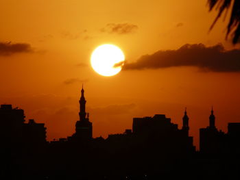 Silhouetted city against dramatic sky during sunset