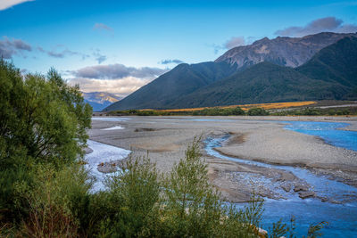 Scenic view of lake by mountains against sky