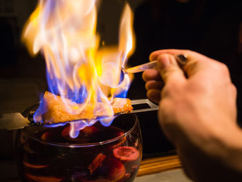 Midsection of person preparing traditional german alcoholic drink feuerzangenbowle