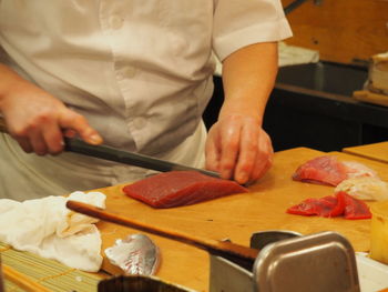 Midsection of male chef preparing sushi on table in kitchen