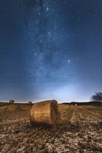 Hay bales on field against sky at night