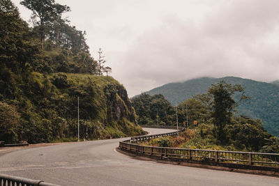 Road by trees against sky