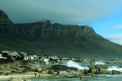 Buildings by mountain against sky