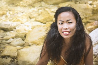 Portrait of smiling young woman standing on rock