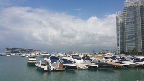 Sailboats moored in harbor against buildings in city