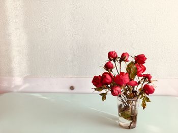 Close-up of red flower vase on table against wall