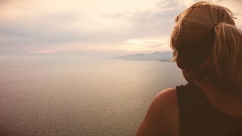 Rear view of woman against sea during sunset