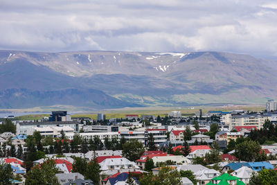 Aerial view of townscape and mountains against sky