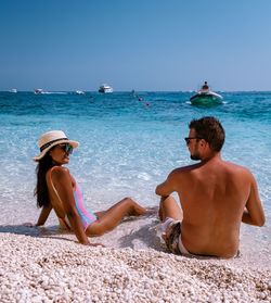 Rear view of couple sitting on beach