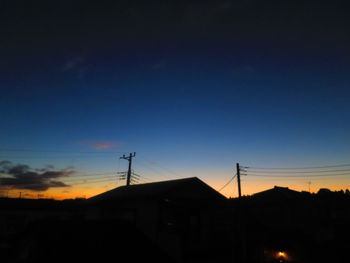 Silhouette houses against sky at sunset