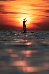 Silhouette man standing at beach during sunset