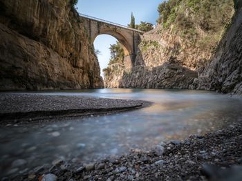 Arch bridge over river amidst rock formations
